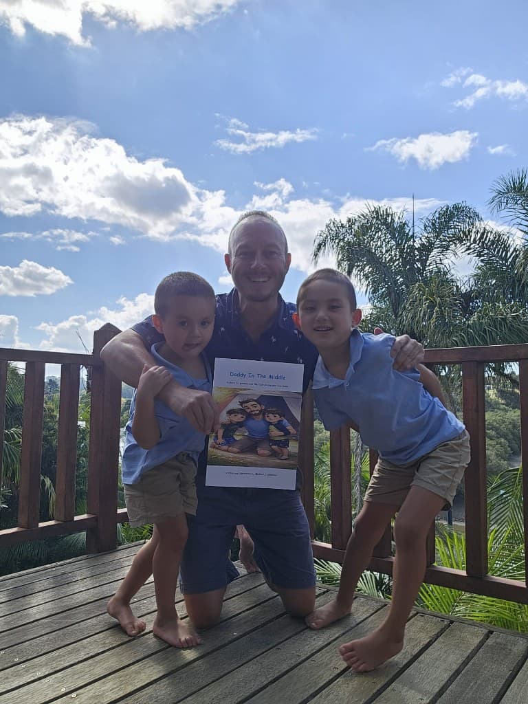 Michael with his two boys holding the Daddy In The Middle book